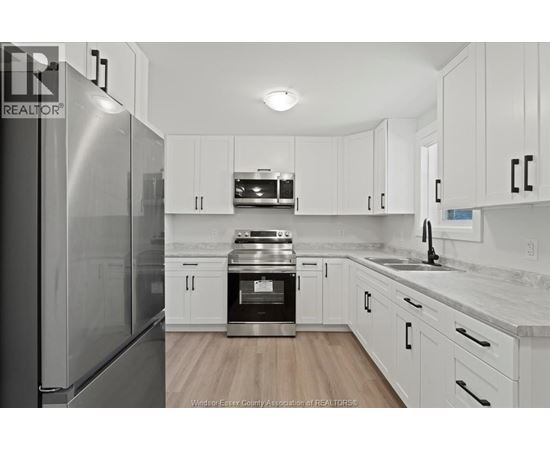 A kitchen with white cabinets and a stainless steel refrigerator.