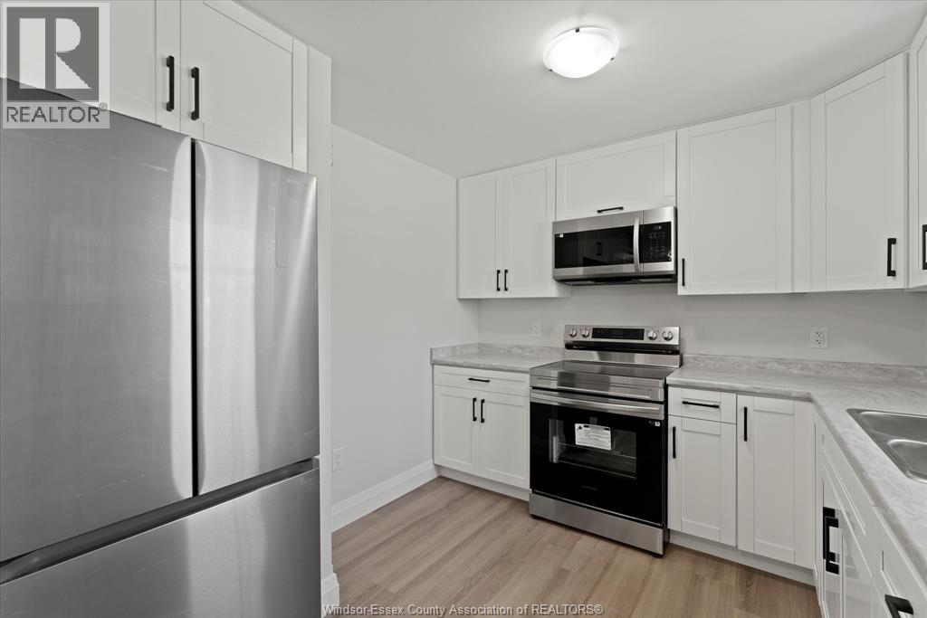 A kitchen with white cabinets and a stainless steel refrigerator.