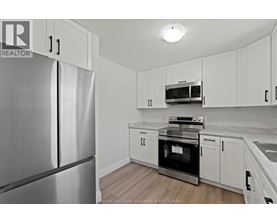 A kitchen with white cabinets and a stainless steel refrigerator.