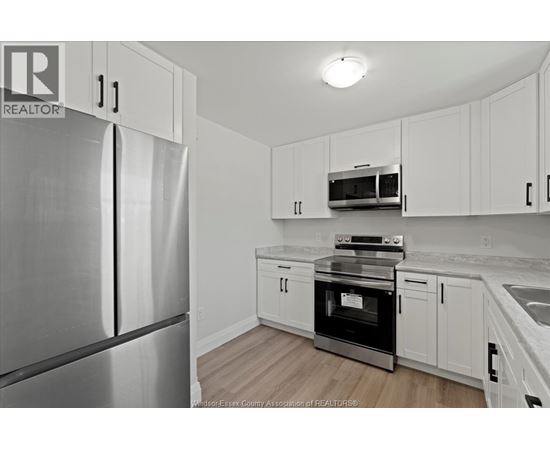 A kitchen with white cabinets and a stainless steel refrigerator.