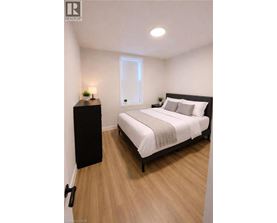 A bedroom with a bed, nightstand, and lamp.
