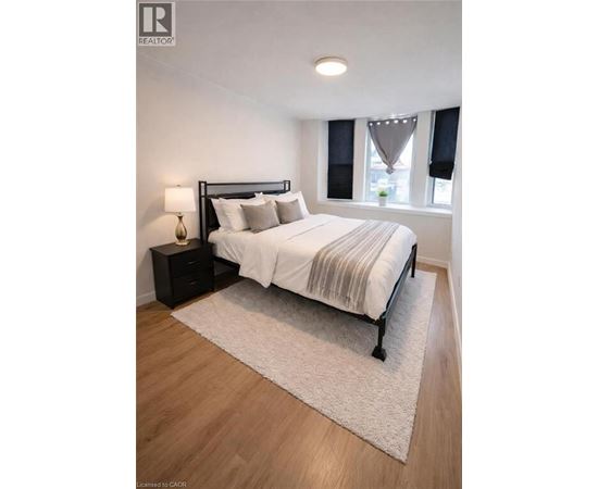 A bedroom with a bed, nightstand, and window.