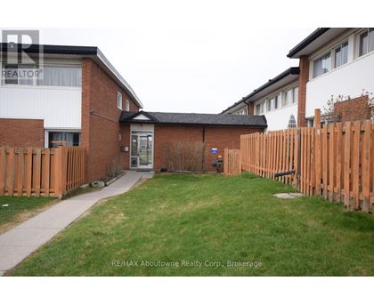 A small grassy yard with a wooden fence and a brick building in the background.