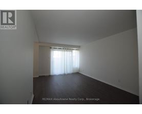 A large empty room with a window covered in white curtains.