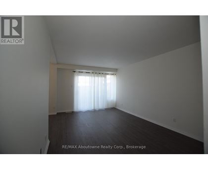 A large empty room with a window covered in white curtains.