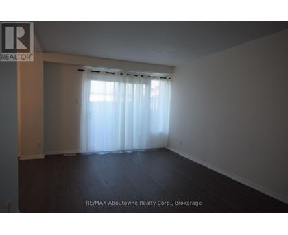 A large empty room with a window covered by sheer curtains.