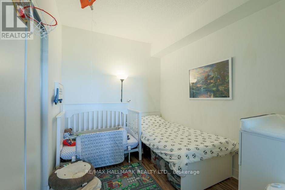 A small bedroom with a white crib and a white bed with a black and white patterned cover.
