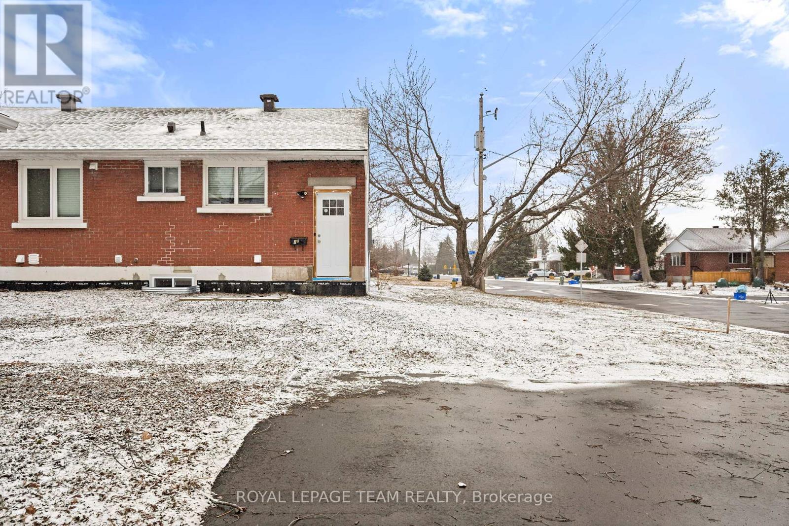 A red brick house with a white door and windows is surrounded by snow.