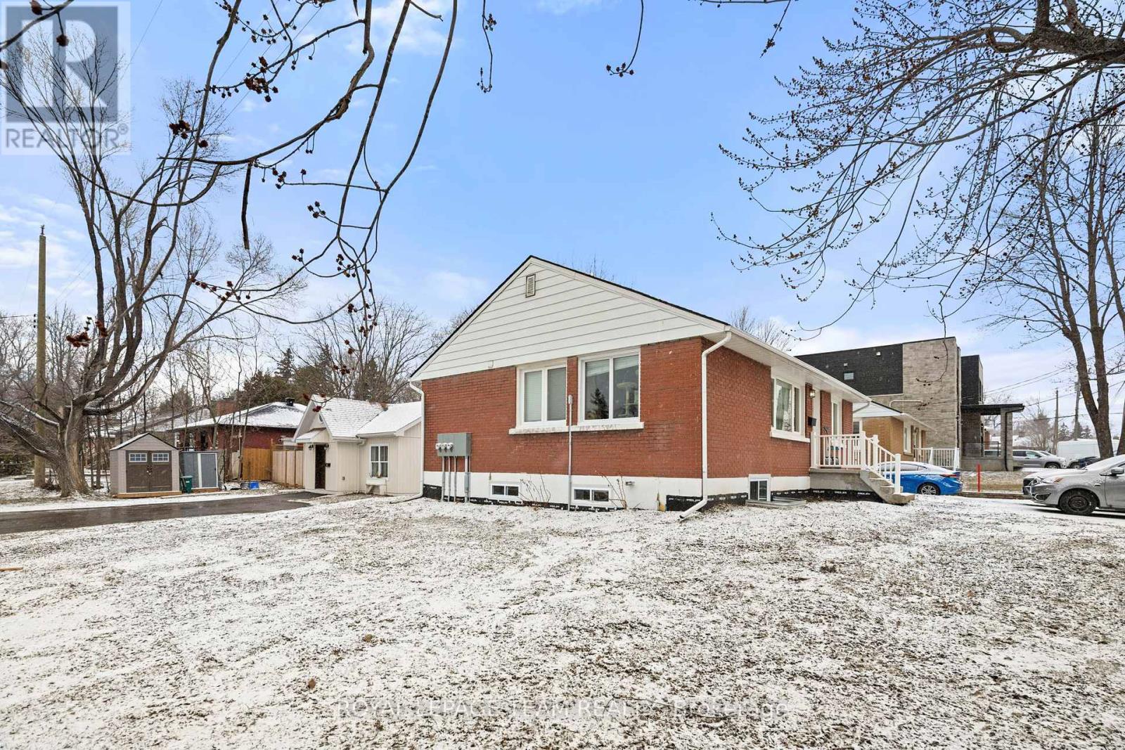 A house with a red brick exterior and a white roof is surrounded by snow.