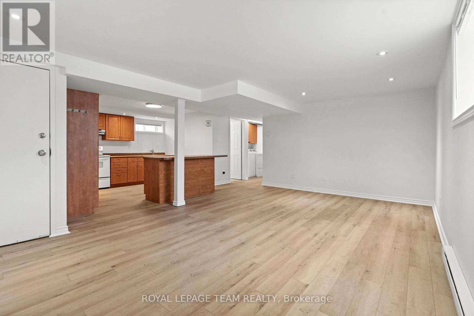 A spacious room with wooden flooring and white walls, with a doorway leading to another room.