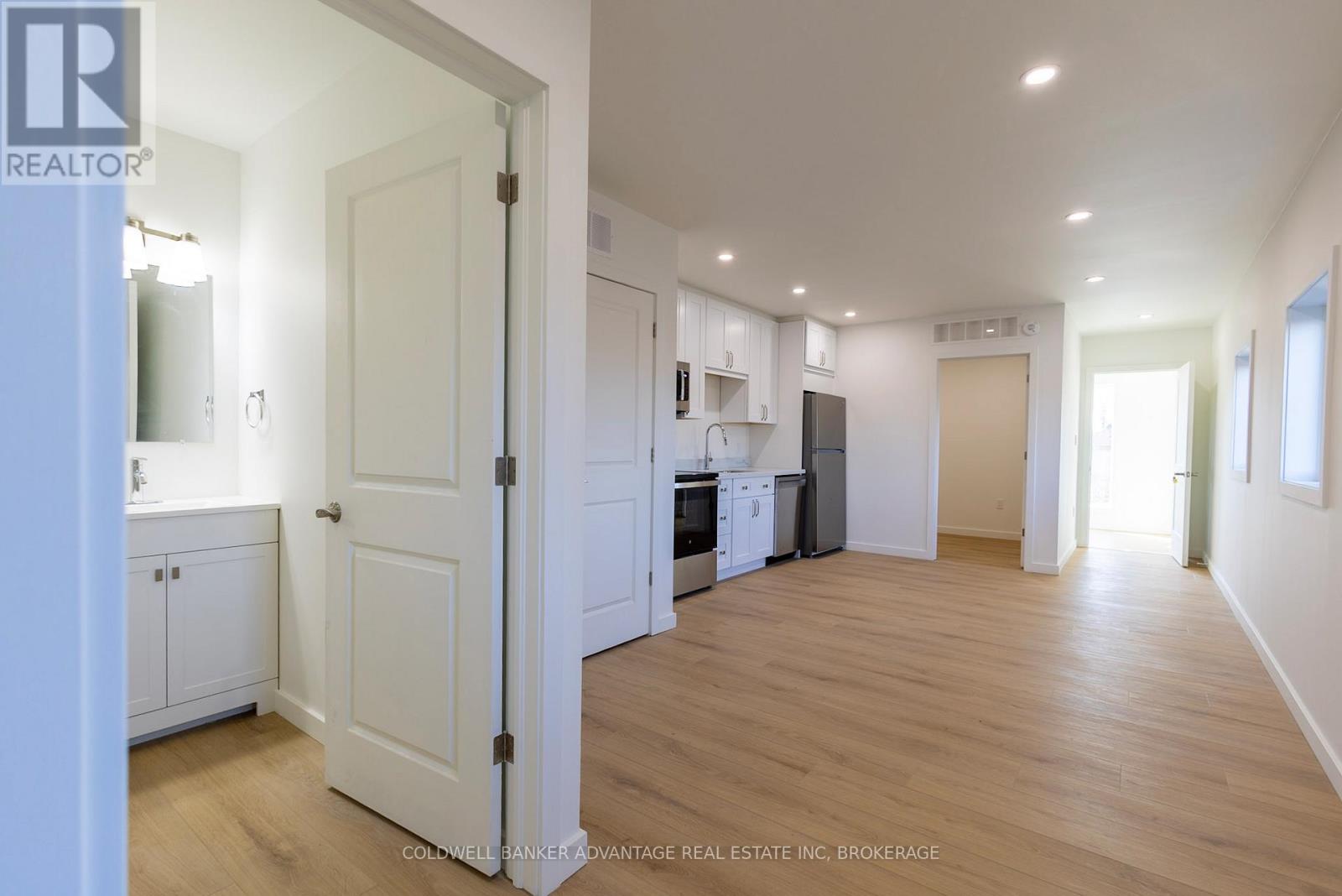 A spacious kitchen with white cabinets and a white door leading to another room.