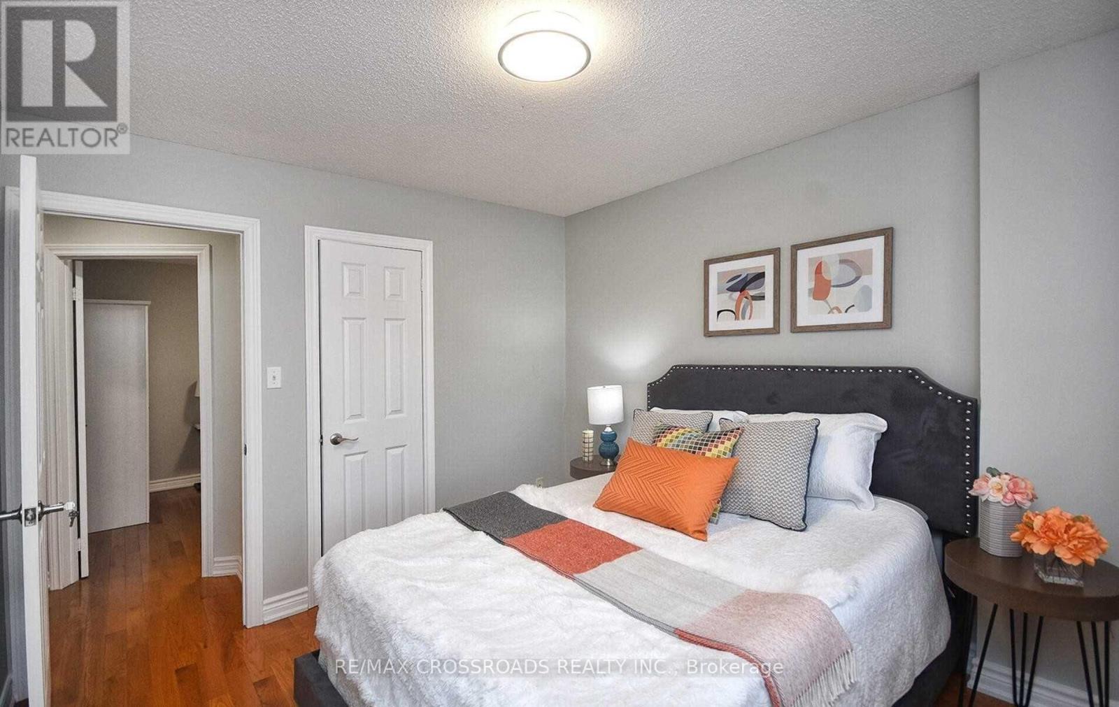 A bedroom with a bed, nightstand, and two pictures on the wall.