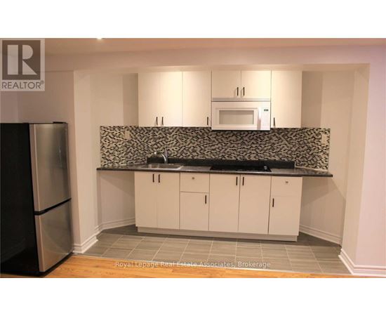 A kitchen with white cabinets and a black and white backsplash.