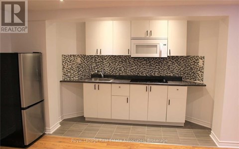 A kitchen with white cabinets and a black and white backsplash.