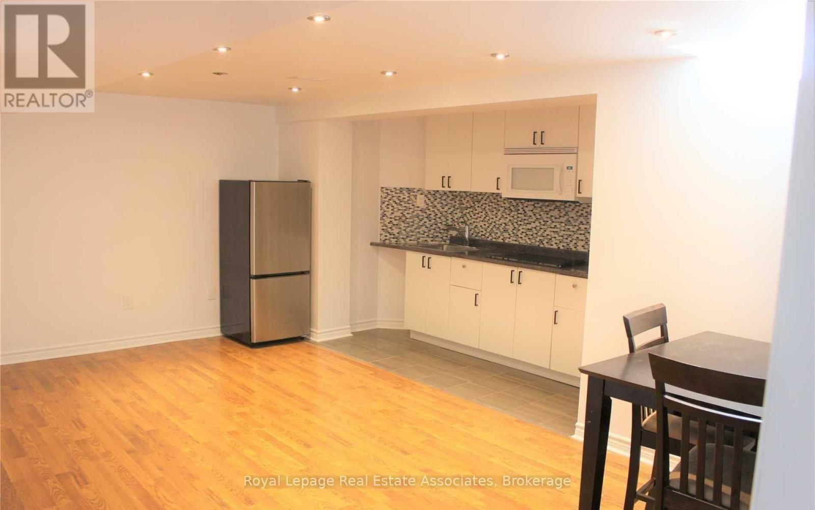 A kitchen with a refrigerator, cabinets, and a table.