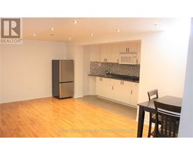 A kitchen with a refrigerator, cabinets, and a table.