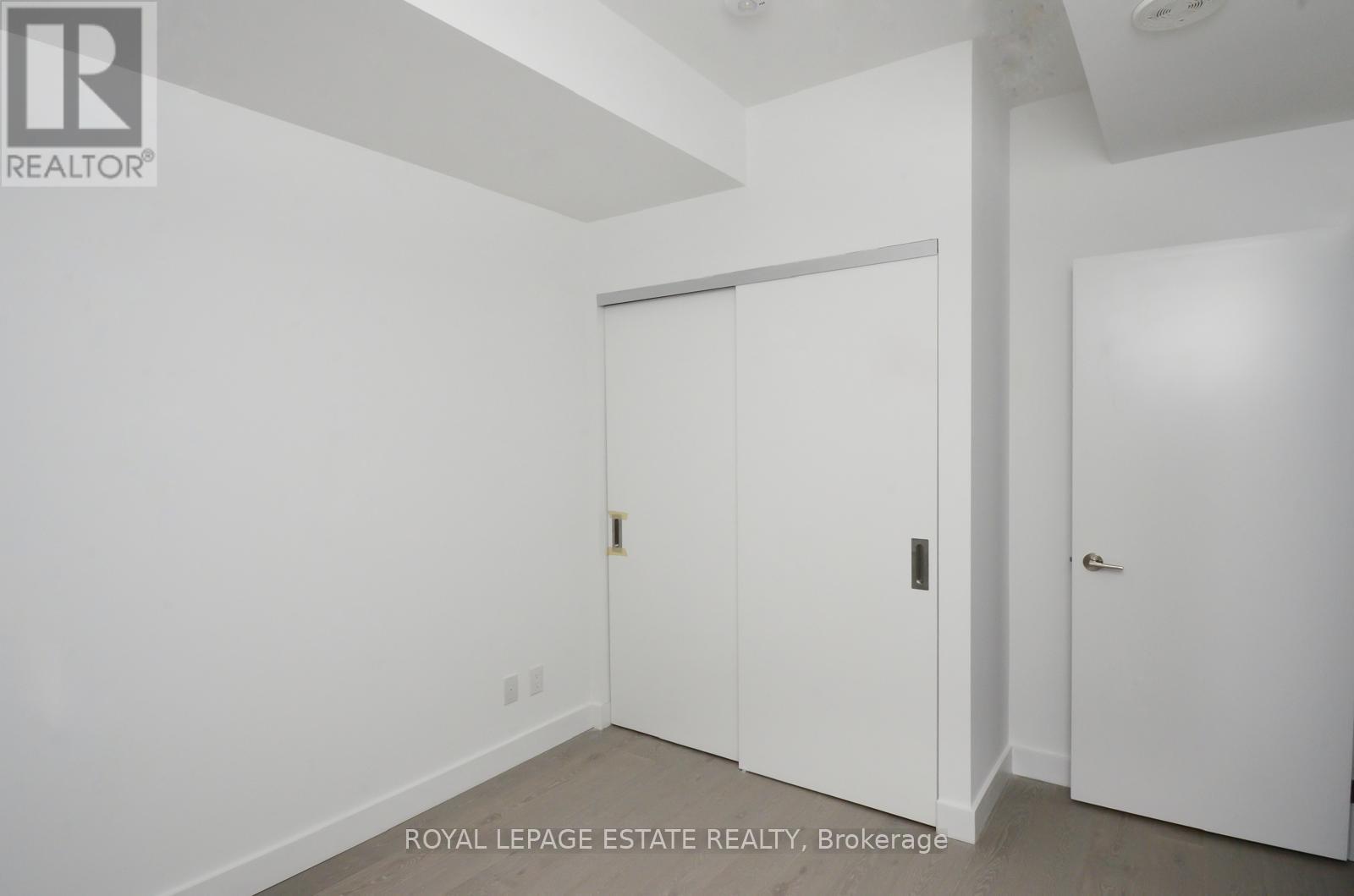A white door is in the middle of a room with a white wall.