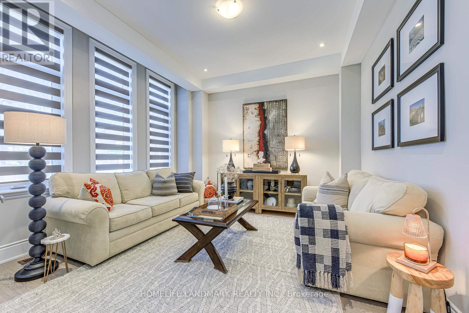 A well-lit living room with a beige sofa, a wooden coffee table, and a side table with a lit candle.