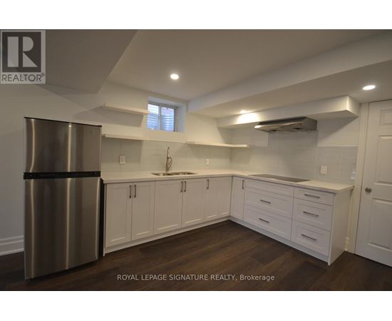 A modern kitchen with white cabinets and a stainless steel refrigerator.
