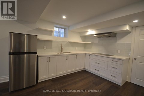 A modern kitchen with white cabinets and a stainless steel refrigerator.