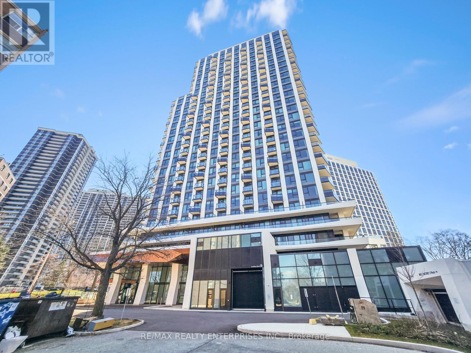 A modern building with a glass facade stands tall against a clear sky.