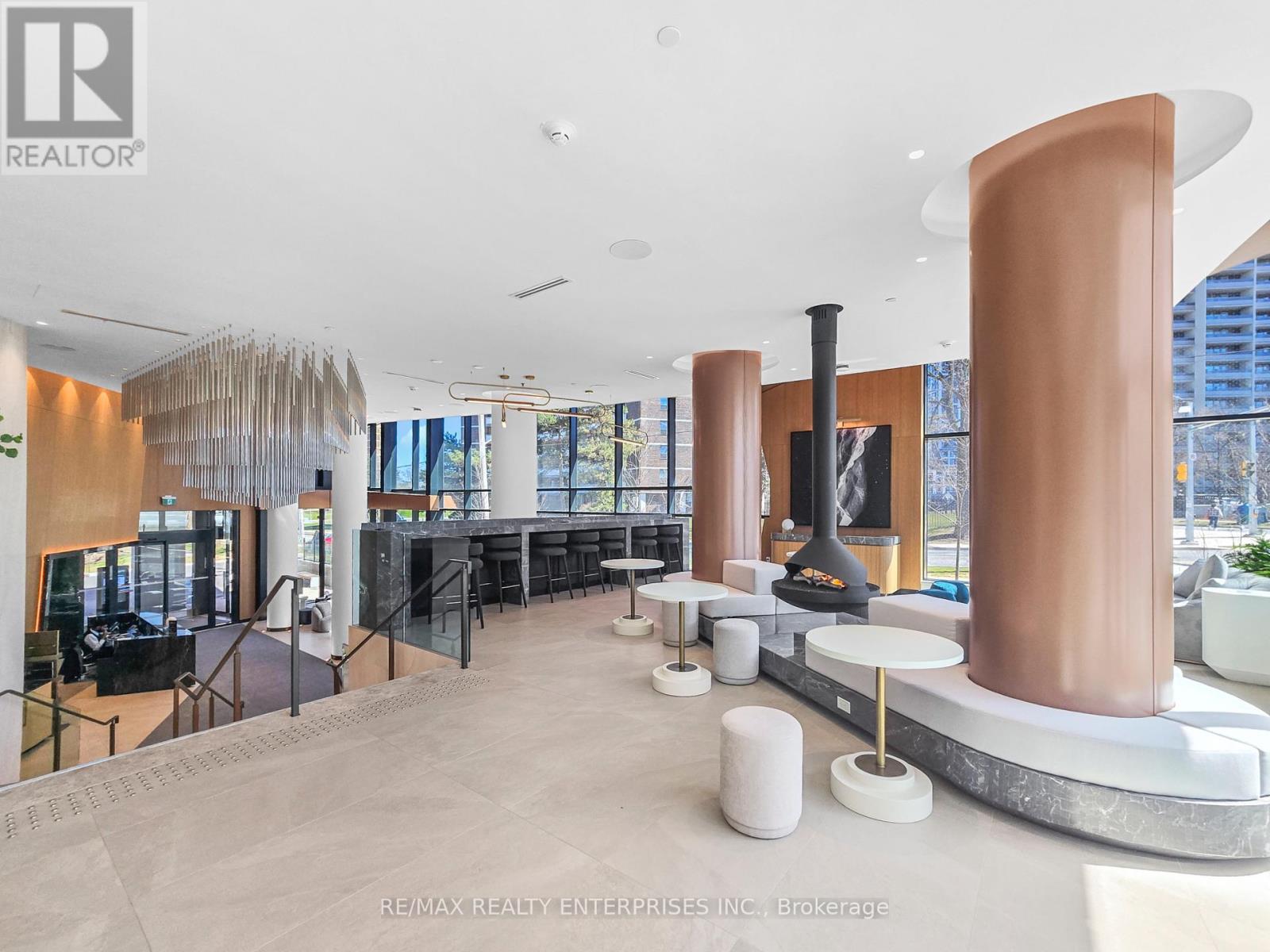 A modern interior space with a large copper column and a fireplace.