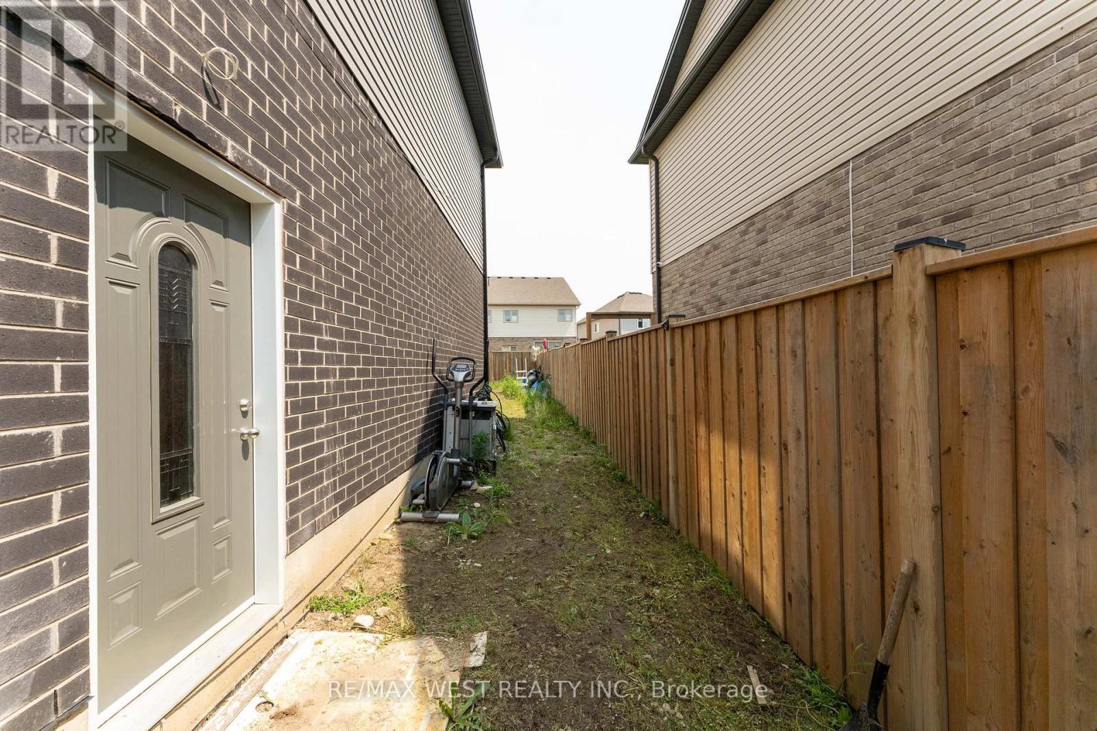 A narrow alley with a wooden fence on one side and a brick building on the other.