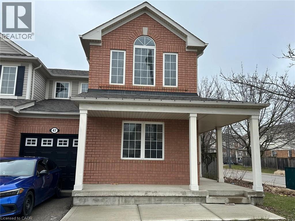 A blue car is parked in front of a brick house with a porch.