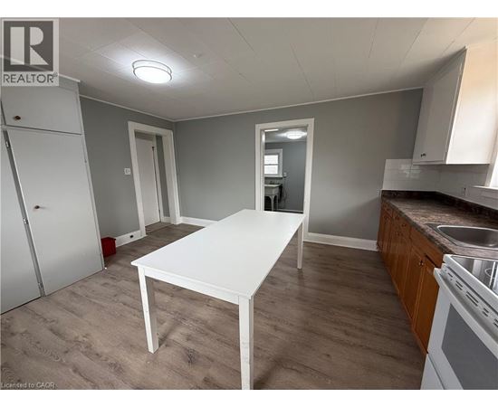 A white table is in the middle of a room with a sink and cabinets.