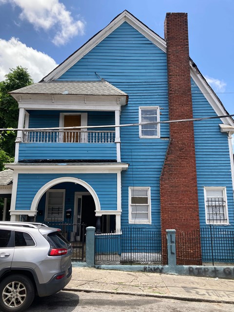 A blue house with a red chimney and a car parked in front.