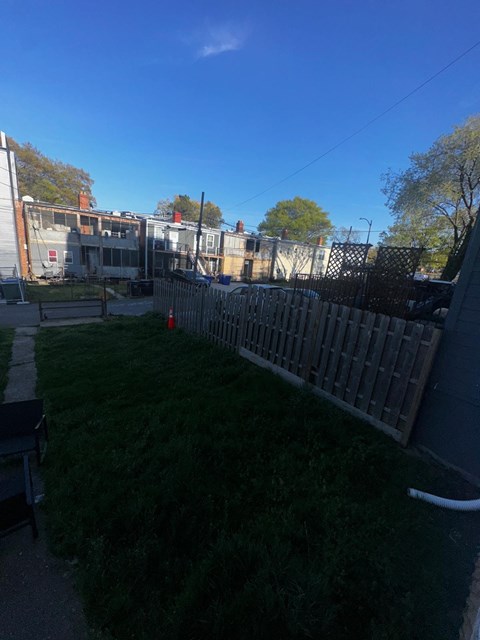 A backyard with a fence and a building in the background.