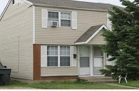 A house with a brown and beige exterior and a white door.
