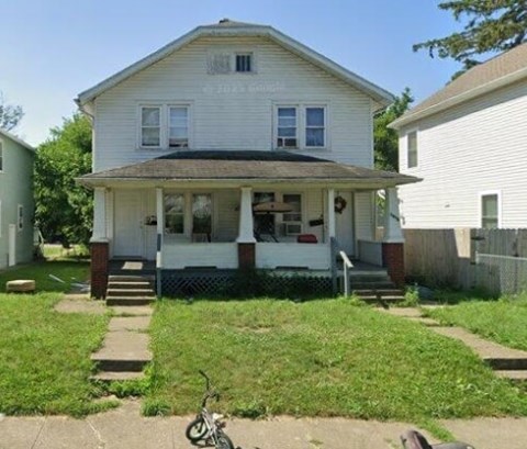 A white house with a porch and a bicycle in front.