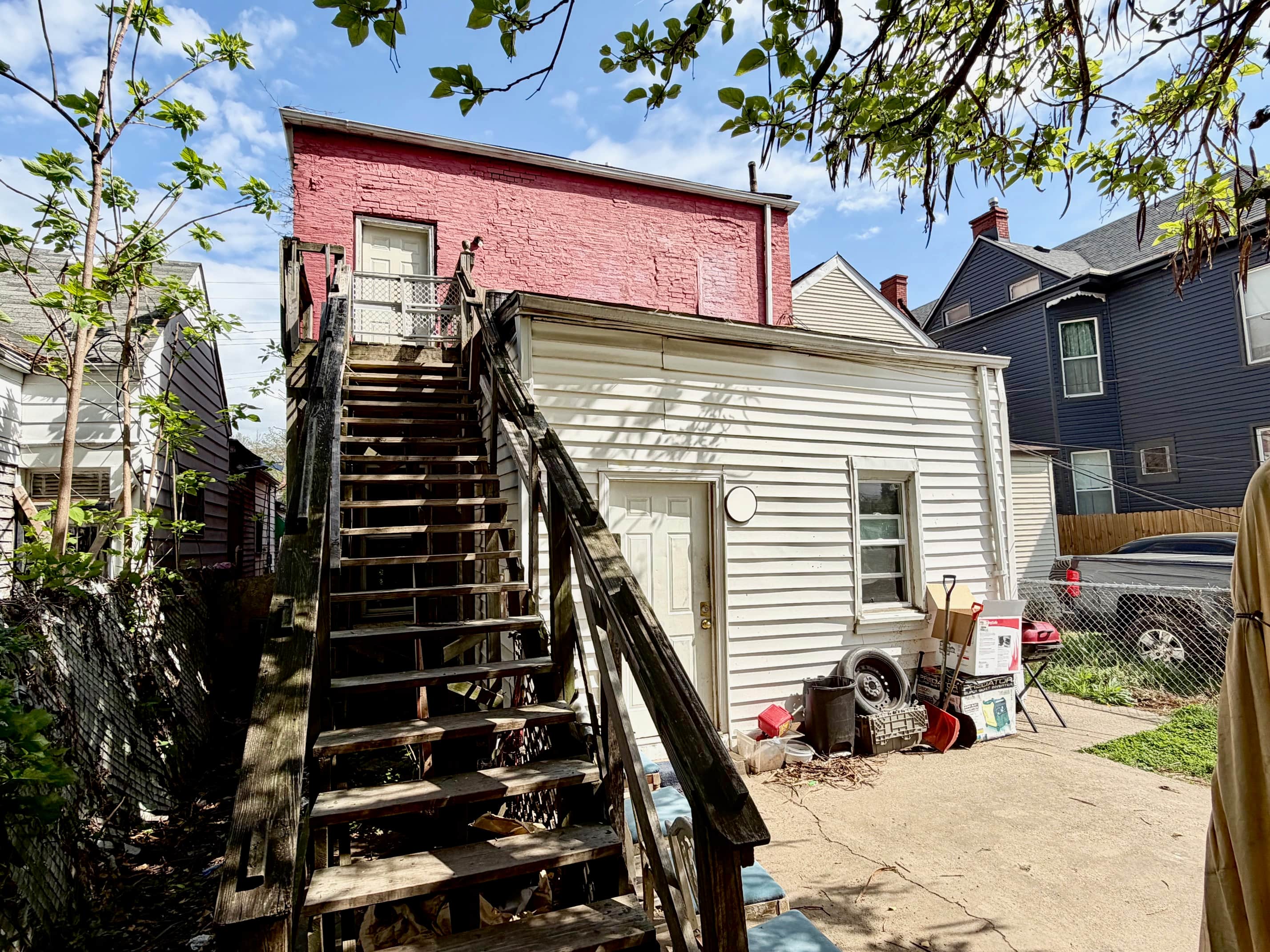 A house with a red brick wall and a wooden staircase leading to a door.