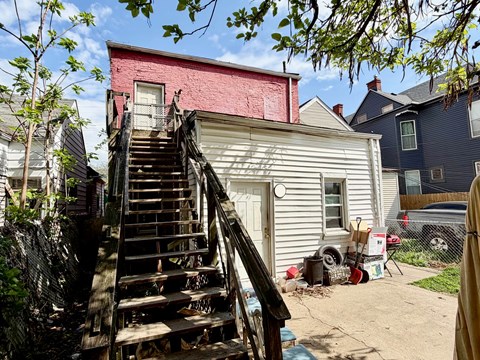 A house with a red brick wall and a wooden staircase leading to a door.