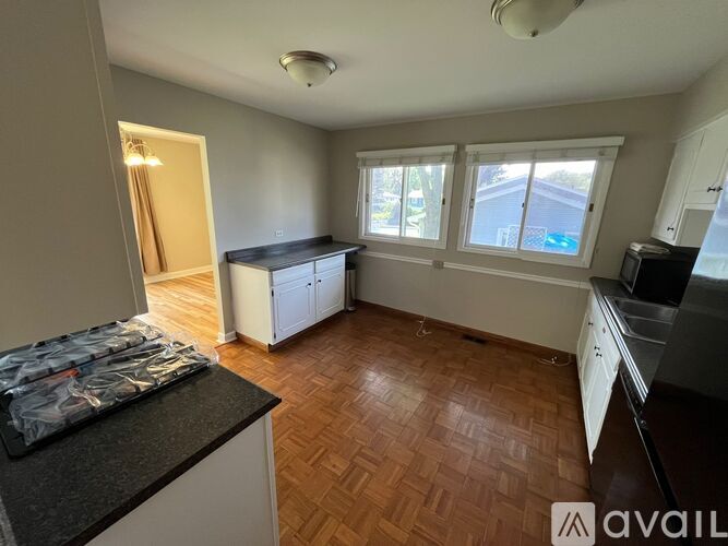 A kitchen with wooden floors and white cabinets.