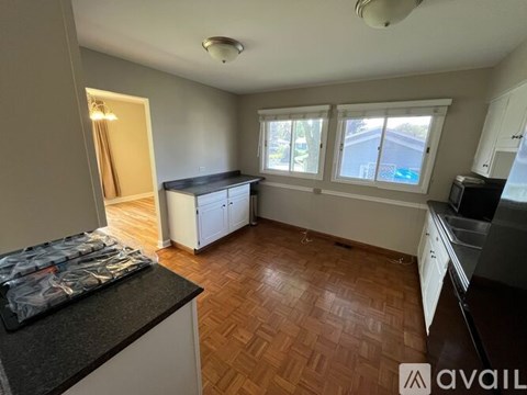 A kitchen with wooden floors and white cabinets.