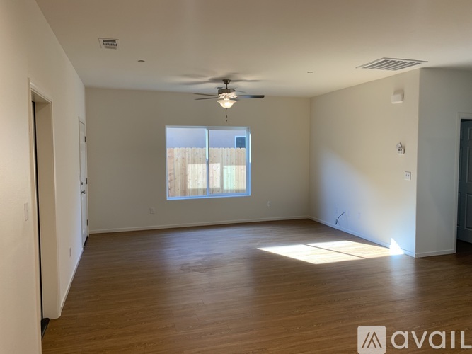 A spacious room with wooden flooring and a ceiling fan.