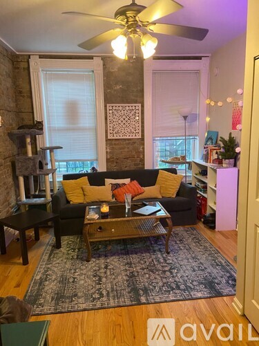 A living room with a couch, coffee table, and a fan.