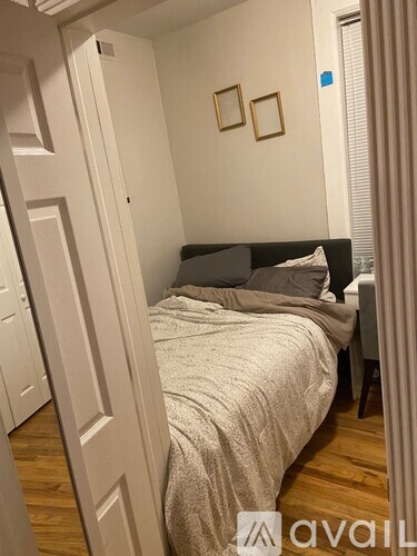 A bedroom with a bed, a chair, and two picture frames on the wall.