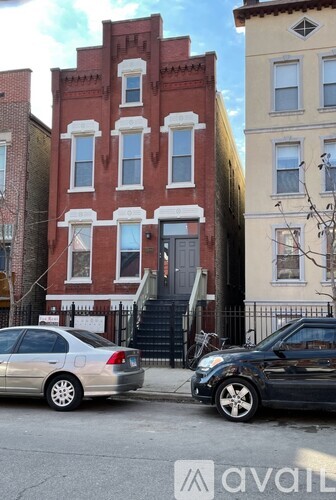 A silver car is parked on the street in front of a red brick building.