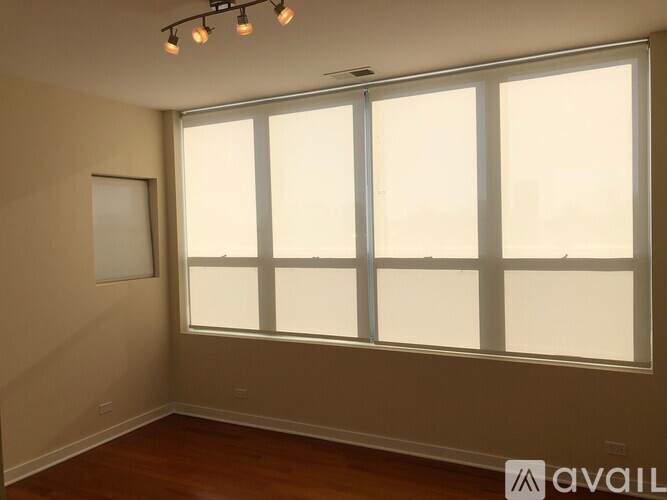 A room with a large window and a picture frame on the wall.