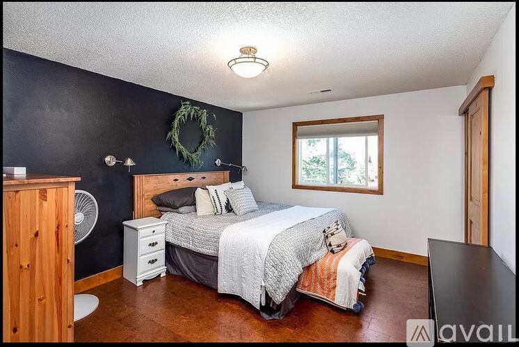 A bedroom with a bed, nightstand, and a wreath on the wall.