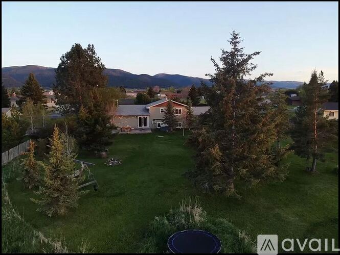 A house surrounded by trees with mountains in the background.
