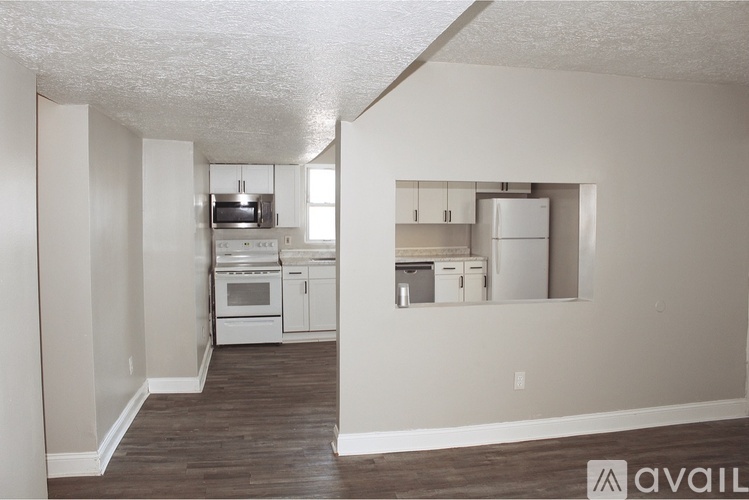 A kitchen with white appliances and wooden floors.