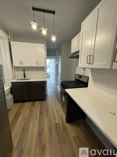 A kitchen with white cabinets and a wooden floor.