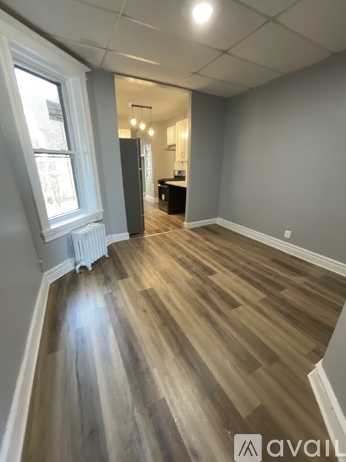A room with wooden flooring and a window on the left side.