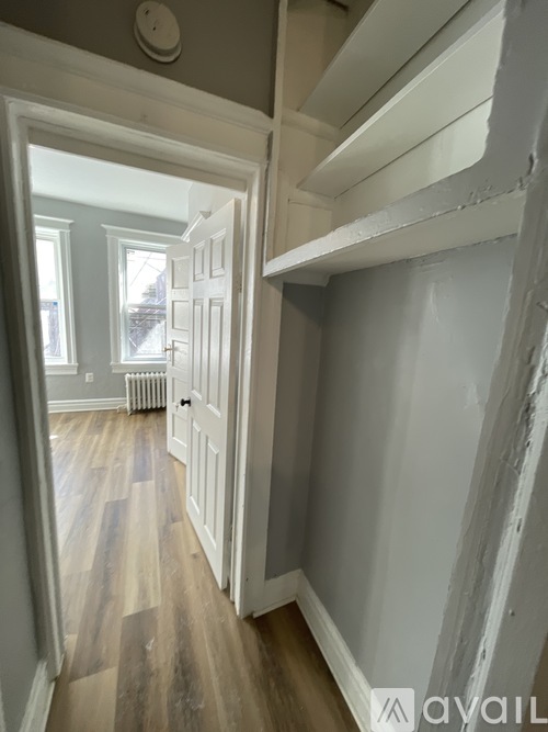 A hallway with a white door and wooden floors.