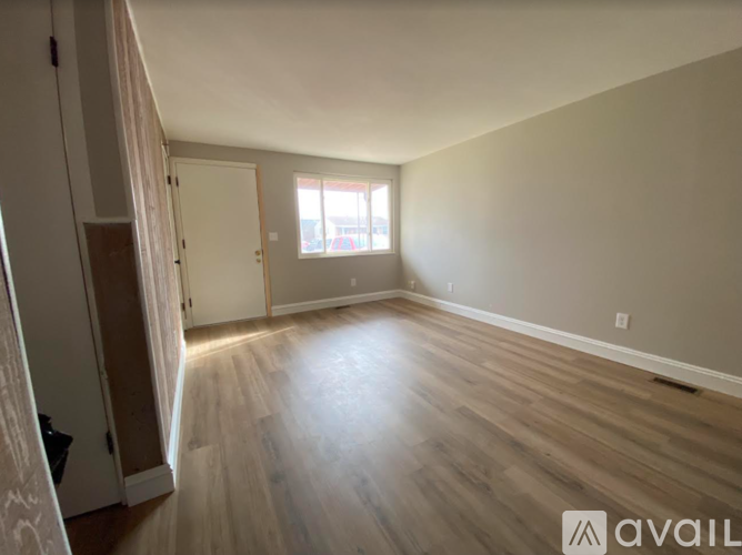 A room with wooden flooring and a window letting in sunlight.