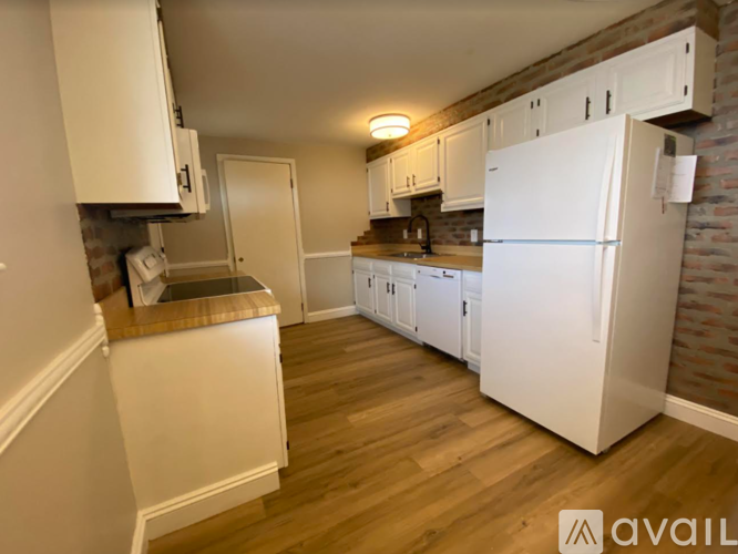 A kitchen with white appliances and wooden floors.
